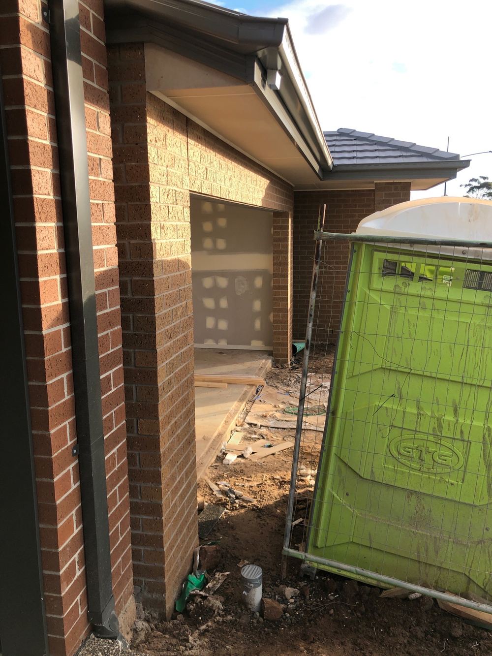 Downpipes still not connected, so roof water lands at the slab edge, found during a fixing inspection in Truganina