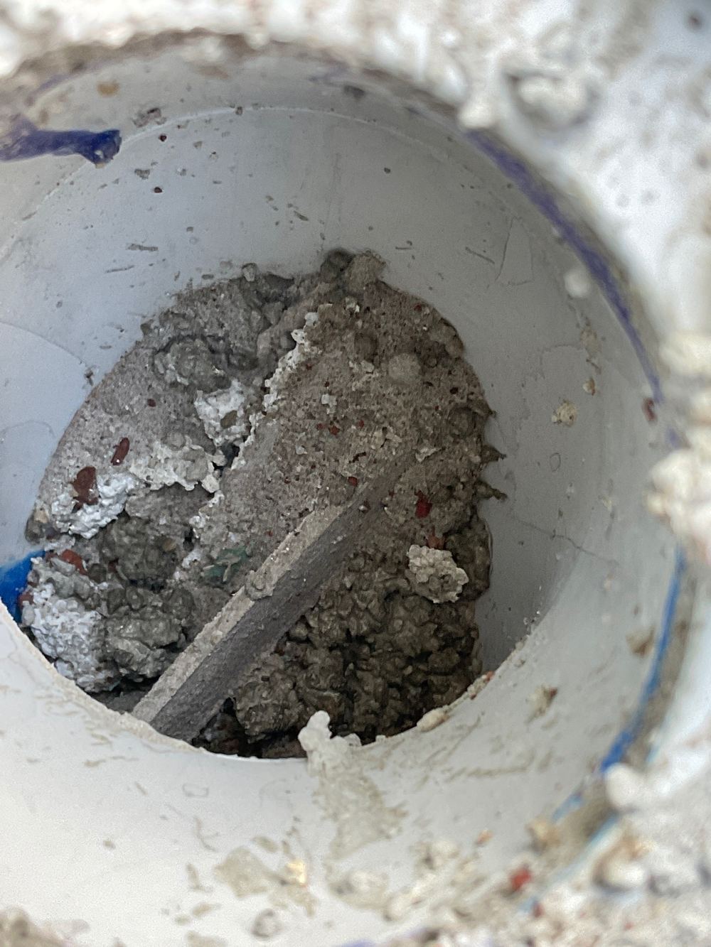 Cement left in a wet area drain where it will set and cause a blockage, found during a construction stage inspection in Truganina